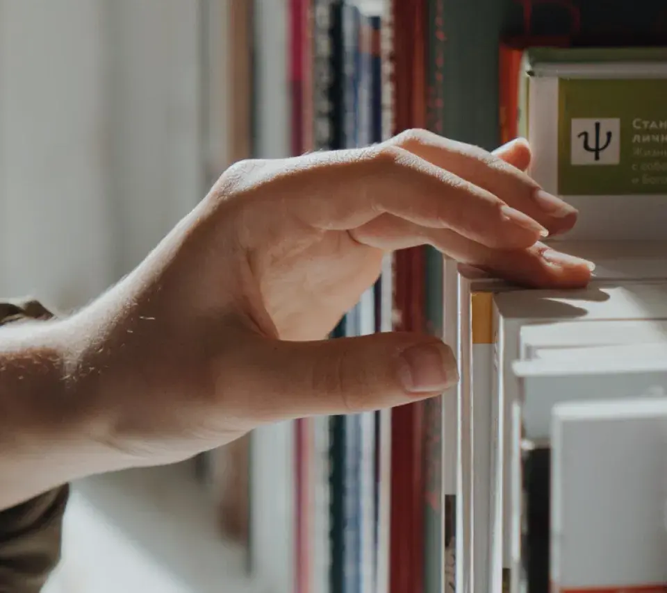 Une main prend un livre sur une étagère