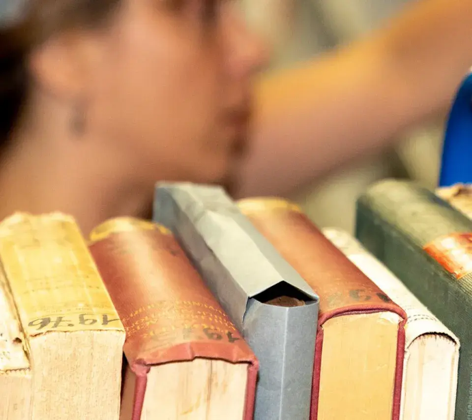 Chariot de livres face à une étagère de bibliothèque, une personne en fond