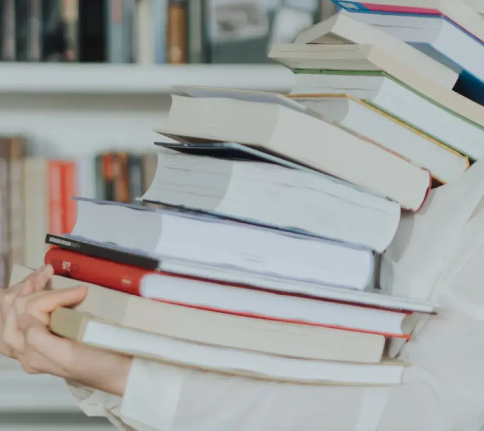 Pile de livres dans les bras d'une personne