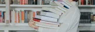 Pile de livres dans les bras d'une personne